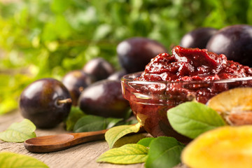 Jam of healthy organically grown plums with plum fruits on a wooden table background