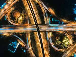 Fototapeta na wymiar Beautiful roundabout intersection at night view. Aerial view of circle transportation in the city with colorful light. Drone view from night sky.