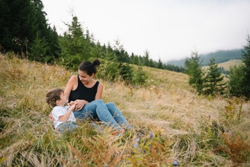 Naklejka na ściany i meble Young mom with baby boy travelling. Mother on hiking adventure with child, family trip in mountains. National Park. Hike with children. Active summer holidays.