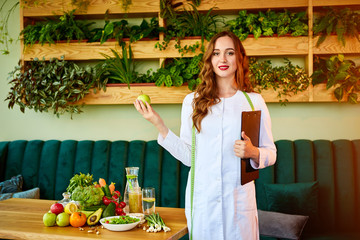Woman dietitian in medical uniform with tape measure holds apple standing with different healthy...