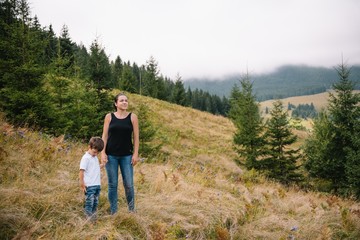 Fototapeta na wymiar Young mom with baby boy travelling. Mother on hiking adventure with child, family trip in mountains. National Park. Hike with children. Active summer holidays.