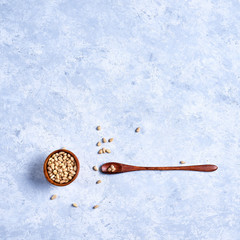 pine nut in a wooden bowl whith wooden spoon on a blue and white background top view