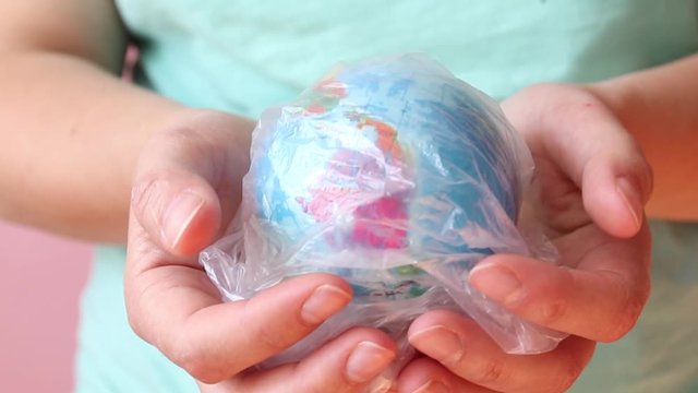 Save the planet concept. Global warming and plastic emissions. Female hand holds planet earth ball in a plastic bag. Zero waste