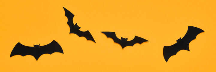 Halloween and decoration concept. Black paper bats flying over orange background. Halloween banner.