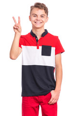 Portrait of teen boy making Victory gesture, isolated on white background. Handsome caucasian young teenager smiling and showing victory sign. Happy cute child doing victory symbol.