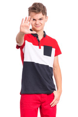 Teen boy doing stop sign with palm of hand, isolated on white background. Beautiful caucasian teenager making stop gesture with negative and serious facial expression. Angry child looking at camera.