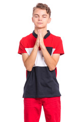 Portrait of teen boy praying, isolated on white background. Cute caucasian teenager with hands folded in prayer hoping for better. Child asking God for good luck, success or forgiveness.
