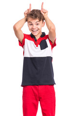 Portrait of teen boy doing bull horns, isolated on white background. Beautiful caucasian teenager making sign with his fingers behind head as if it is horns. Child showing horns cow and mooing.