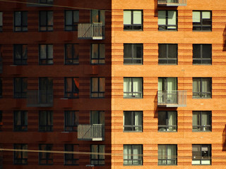 Fototapeta na wymiar Corner of a house with Windows and balconies. One side is illuminated by the sun