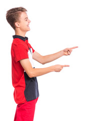 Excited teen boy pointing fingers away at copyspace - side view, isolated on white background. Cute teenager smiling and laughing pointing fingers at something. Happy child looking away - profile.