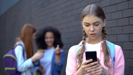 Embarrassed female teenager reading humiliating news in social networks, abuse