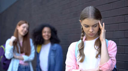 Humiliated pupil suffering classmates bullying on backyard, psychological trauma
