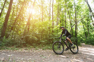 Fototapeta na wymiar Male cyclist riding on forest trails in sun flare