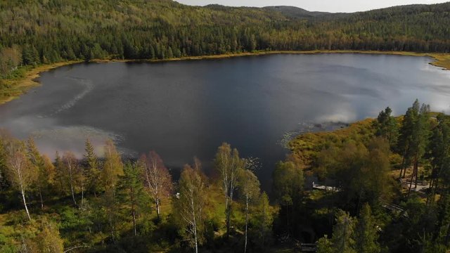 Aerial view over a beautiful still blue water lake surrounded by forest at Heisetra cabin in Kodal, Norway