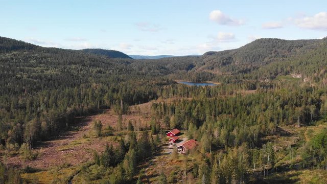 Aerial view over Heisetra cabins with a small lake and lots of pine trees and forest surrounding the cabins, in Kodal, Norway