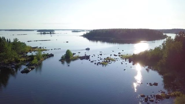 Aerial tracking drone shot, following a motorboat driving between small islands in Northern Europe on a sunny summer day