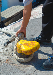 Sailor ties a boat to a harbor bollard