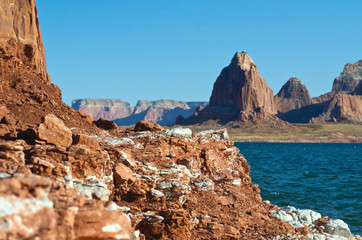 The layered red rock shoreline in front of the warm desert lake. 