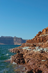 The layered multi colored rocky shoreline in the wide open canyon. 