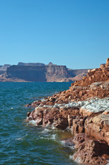 The red and white rocky shore line in the canyon of the grand lake powell. 