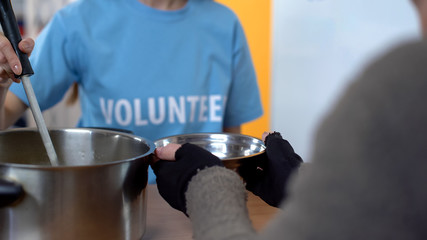 Female volunteer serving soup in shelter, care of poor people, charity project