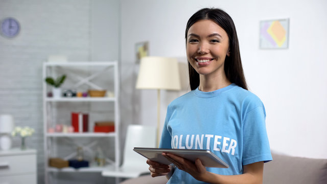 Cheerful Volunteer With Tablet Smiling Camera, Online Fundraising Application