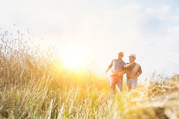 Mature showing wheat field to senior farmer with yellow lens flare in background