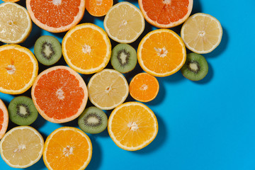 Fresh summer fruits on blue background. Healthy food concept. Flat lay. Tropical summer mix grapefruit, orange, mandarin, kiwi, lemon