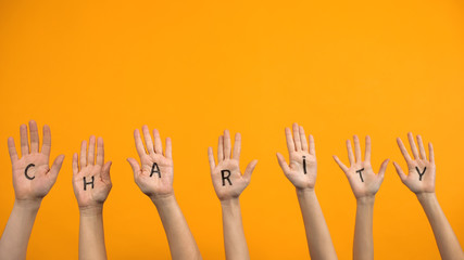 Charity written palms on orange background, donation center, volunteer project