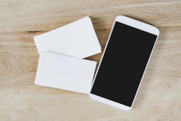 top view of white name card and mobile phone with clipping path on screen , on wooden desk