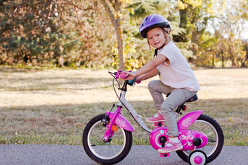 Naklejka premium little girl riding a bicycle during the autumn
