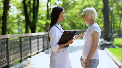 Upset woman talking with doctor in medical clinic park, fatal disease concept