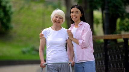 Grandmother with walking frame and young female hugging and smiling at camera