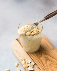 Homemade peanut butter in a jar and chocolate cookies on a cutting board on a concrete background. Perfect breakfast