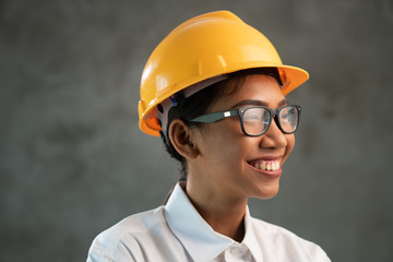 Portrait of smiling attractive Asian woman engineer over concrete wall background