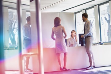 Receptionist calling the manager while business people waiting in lobby