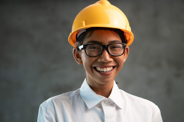 Portrait of smiling attractive Asian woman engineer over concrete wall background