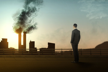Rear view of Asian businessman looking at the chimney and air pollution from the industrial activity