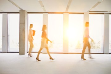 Fototapeta na wymiar Business people walking in office corridor with yellow lens flare in background