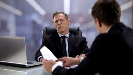 Boss listening male employee talking about profitable project, successful result