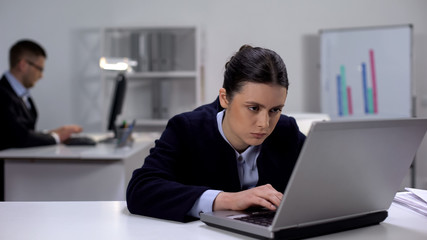 Female manager fighting with sleeping desire at workplace in front of laptop