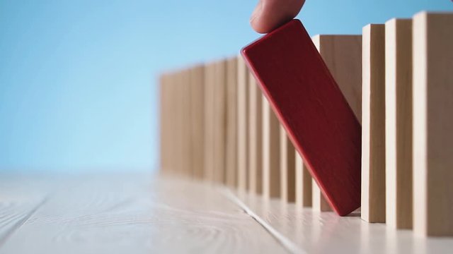 Hand drops red wooden block, standing in row with colorless blocks.