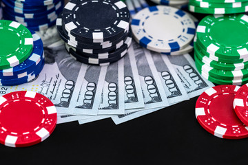 Poker chips and dollar on black background