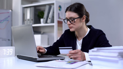 Lady in suit entering card number in online shopping store, internet transaction