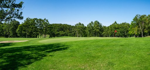 Fototapeta premium Panoramiczny widok na pole golfowe z pięknym putting green. Pole golfowe z bogatą zielenią w pięknej scenerii.