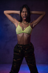 Fototapeta premium Young beautiful fashion Asian girl dancer wearing stylish clothes posing in studio with neon lights