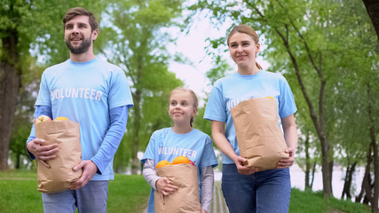 Volunteers family walking park holding paper bags with apples and oranges, help