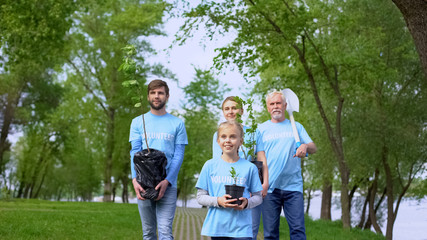 Eco volunteers walking park holding plant saplings shovel, nature conservation