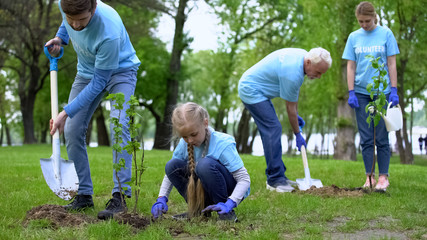 Family environmental volunteers planting trees smiling each other, reforestation
