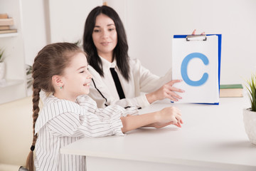 Child with therapist working on pronunciation and sounds together sitting in the class
